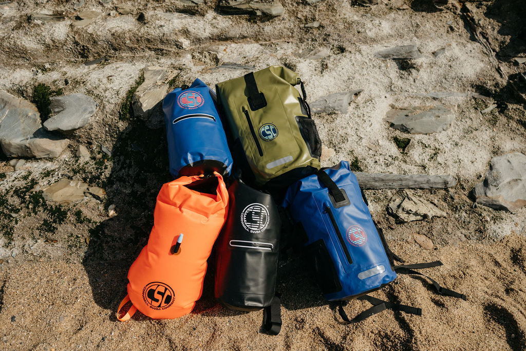 Colorful waterproof swim bags on a rocky beach