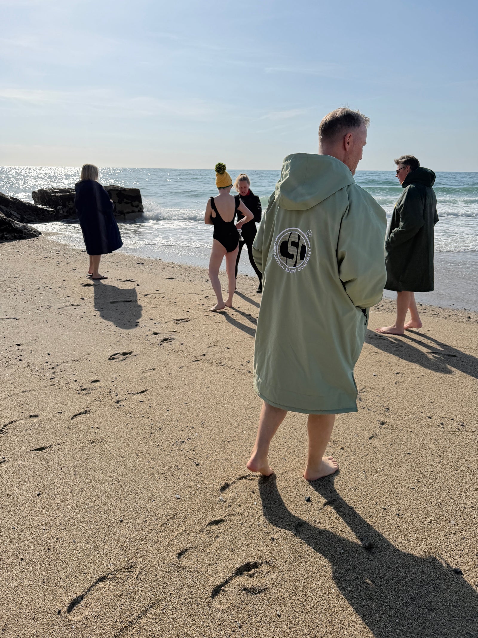 People wearing changing robes on a beach after sea swimming in the UK