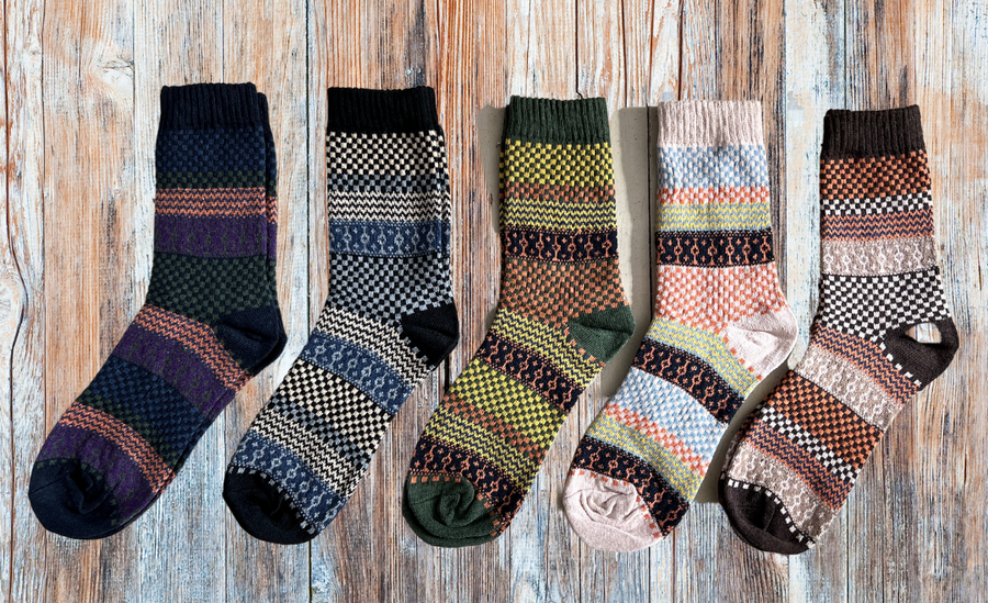 A set of five pairs of colorful socks laid out on a wooden surface, featuring various patterns and colors.